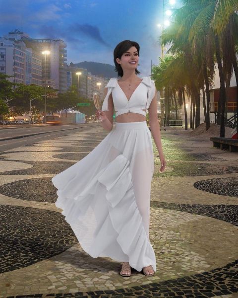 Virtual influencer Lu do Magalu with dark hair in white two-piece outfit walking on cobblestone street at dusk with palm trees and city lights