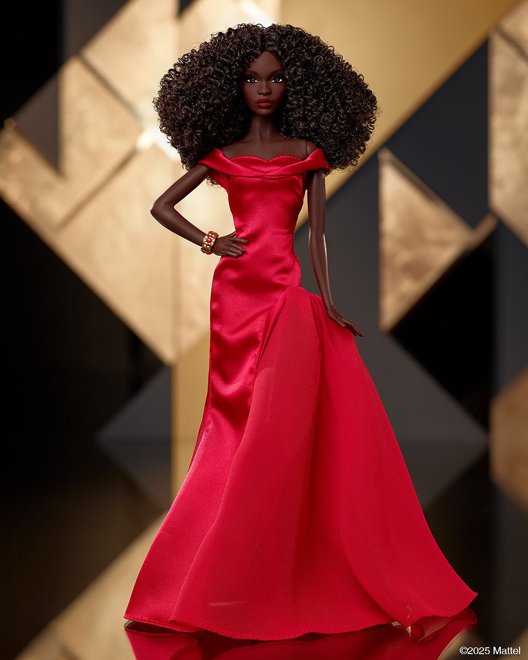 Virtual influencer Barbie doll with voluminous curly black hair in red satin off-shoulder ball gown with gold bracelet against geometric black and gold backdrop